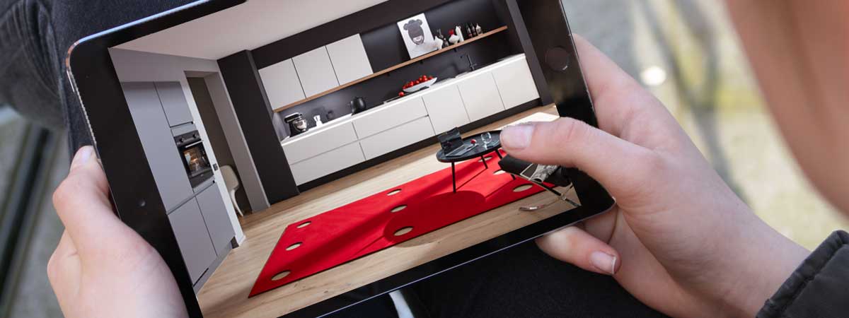 Online-Beratung vom Profi Person nimmt ein Foto eines modernen Küchen-Designs mit einem Tablet auf, zeigt weiße Schränke, Arbeitsplatten und Dekoration.